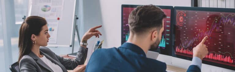 Data analysts pointing on charts on computer monitors while testing security software in office,