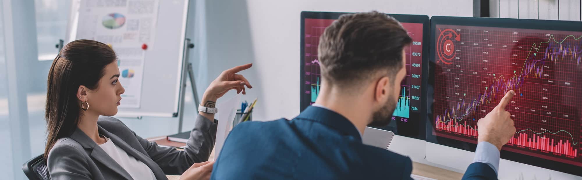 Data analysts pointing on charts on computer monitors while testing security software in office,